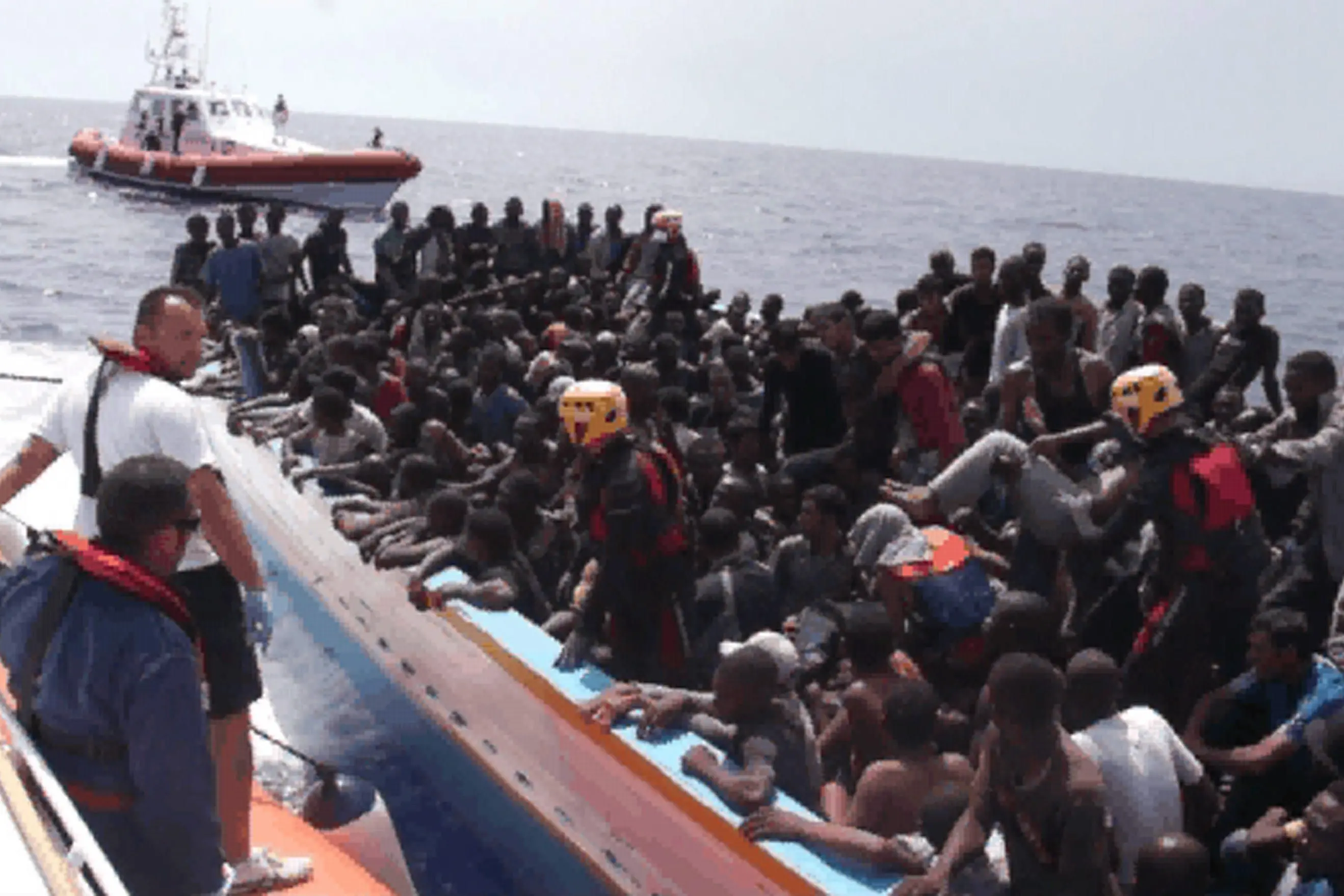 epa02856153 A video grab provided by the Italian Coast Guard released on 05 August 2011 shows the moment around 300 sub-Saharan migrants were rescued after they were found on a barge 166 kilometres from of Lampedusa on 04 August 2011. Italian coast guard officials said on 05 August they had failed to find any trace of dozens of migrants who allegedly died when their refugee boat became stranded in Libyan territorial waters. The search began after Italian authorities rescued a group of around 300 migrants late on 04 August some 90 nautical miles (166 kilometres) from the southern island of Lampedusa. The body of a man was also found on board the boat. Some of the migrants, many of whom were suffering from dehydration, said that around 100 of their fellow passengers, including several children, died during the journey and that their bodies had been thrown into the sea.  EPA/ITALIAN COAST GUARD/HANDOUT BEST QUALITY AVAILABLE HANDOUT EDITORIAL USE ONLY/NO SALES