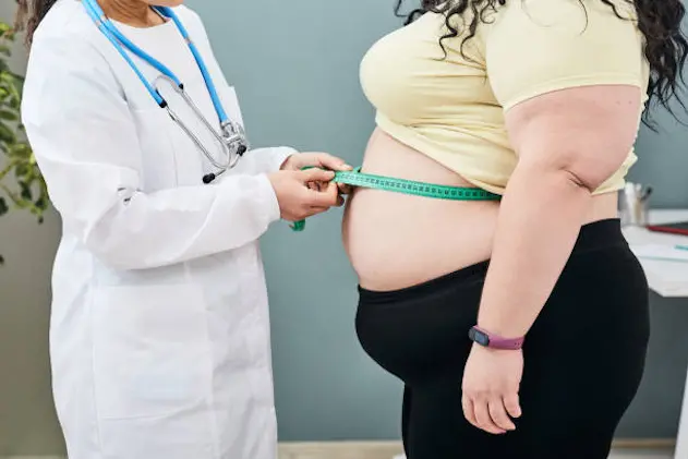 Obesity, unhealthy weight. Nutritionist inspecting a woman\\'s waist using a meter tape to prescribe a weight loss diet