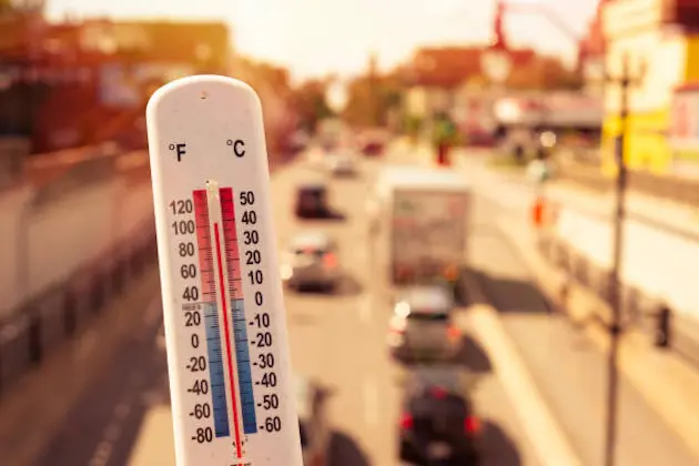 Thermometer in front of cars and traffic during heatwave in Montreal.