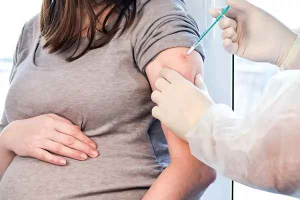 Pregnant Vaccination. Pregnant Woman In Face Mask Getting Vaccinated in Clinic. Doctor Giving Corona Virus Vaccine Injection Patient. Covid-19 Flu Protection.