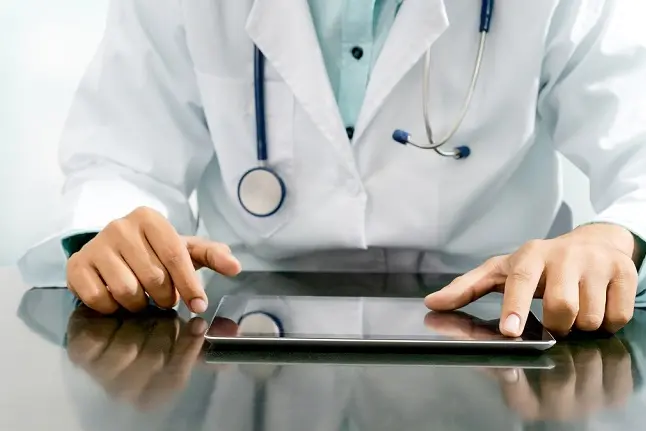 Male doctor sitting at table with tablet computer in hospital office. Medical healthcare staff and doctor service.