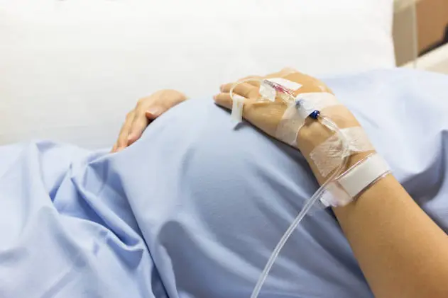 Asian Pregnant Woman patient is on drip receiving a saline solution on bed VIP room at hospital, selective focus.