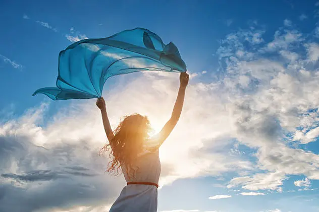 Beautiful young woman on sunset background with blue tissue.