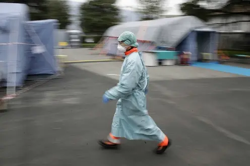 A staffer walks at one of the emergency structures that were set up to ease procedures at the Brescia hospital, northern Italy, Thursday, March 12, 2020. Italians woke up to yet further virus-containment restrictions after Premier Giuseppe Conte ordered restaurants, cafes and retail shops closed after imposing a nationwide lockdown on personal movement. For most people, the new coronavirus causes only mild or moderate symptoms, such as fever and cough. For some, especially older adults and people with existing health problems, it can cause more severe illness, including pneumonia. (AP Photo/Luca Bruno)