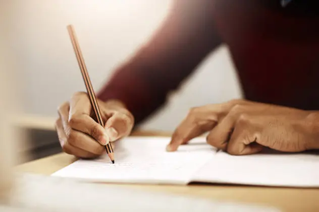 Closeup shot of a university student writing notes in his book