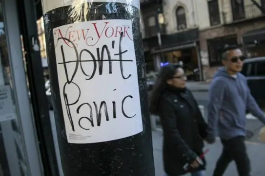People walk past a convenient store where the latest cover of a magazine is stuck on a pillar outside of it on Sunday, March 15, 2020, in New York. President Donald Trump on Sunday called on Americans to cease hoarding groceries and other supplies, while one of the nation\\\\\\'s most senior public health officials called on the nation to act with more urgency to safeguard their health as the coronavirus outbreak continued to spread across the United States. (AP Photo/Wong Maye-E)