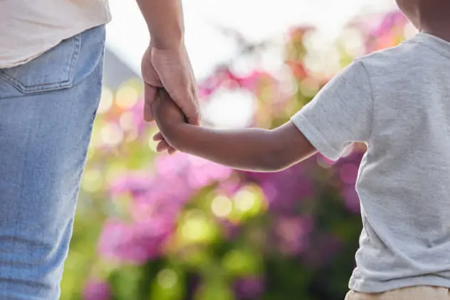 Closeup father and son holding hands while walking outside in the garden. A great role model and mentor for his boy child. A son will always look up to and follow in their dad\\'s footsteps