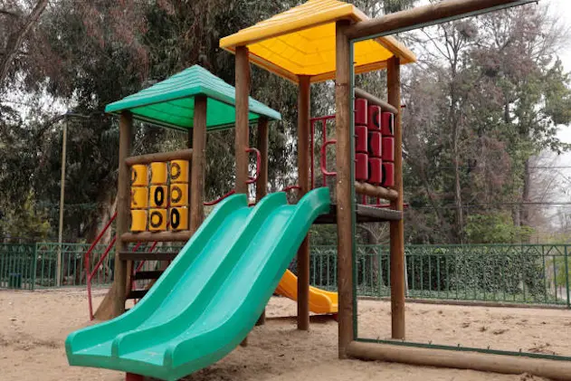 children\\'s playground with slides and stairs on a cloudy day in a city park