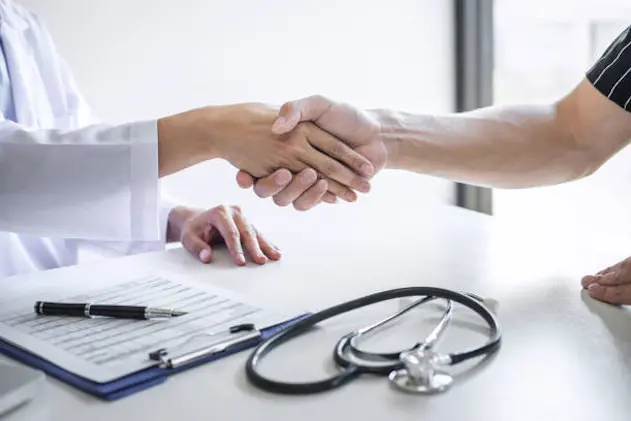 Professional female doctor in white coat shaking hand with patient after successful recommend treatment methods after results about the problem illness, Medicine and health care concept.