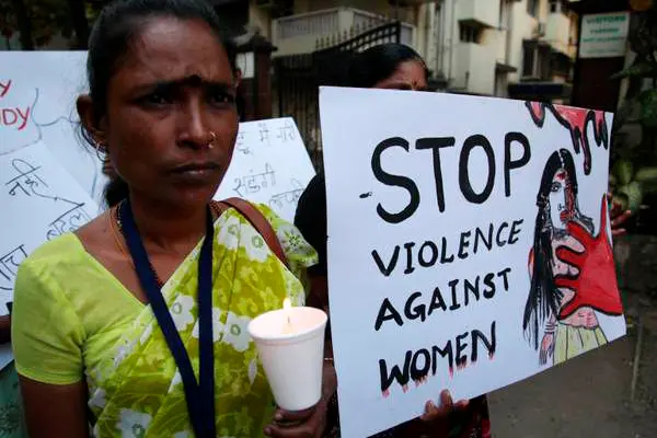 epa03518670 An Indian protester holds a candle and others placards, during a silent protest march held by sex workers, transgender and gays, against the gang rape of a student in New Delhi a week back, in Mumbai, India, 27 December 2012. The 23 year old woman who was gang-raped by 6 men on a moving bus on the night of 16 December 2012 has been flown to a Singapore hospital for further treatment of her severe internal injuries.  EPA/DIVYAKANT SOLANKI