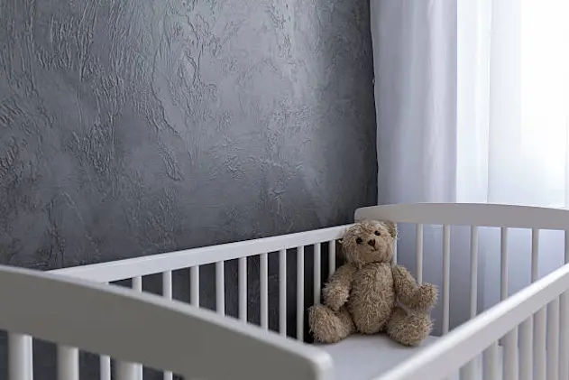 Shot of a teddy bear sitting in a crib