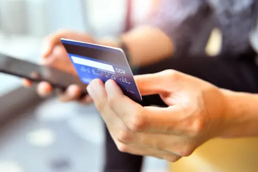 Hands holding a credit card and using smart phone for online shopping