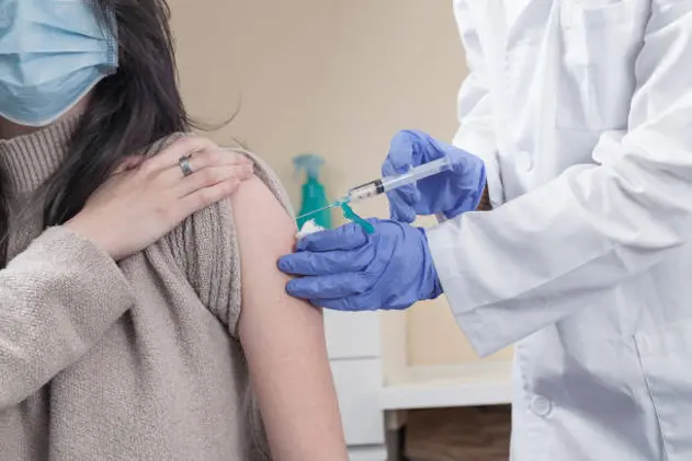 Covid-19 vaccination campaign concept with syringe applyed by doctor on a woman arm.