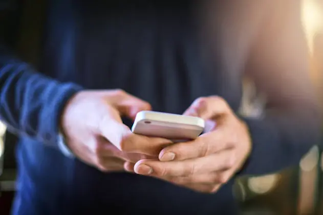 Closeup shot of an unrecognizable university student using a cellphone at campus