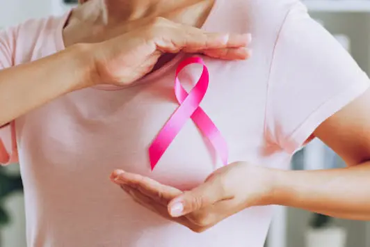 Asian woman show pink ribbon as sign of October Breast Cancer Awareness month