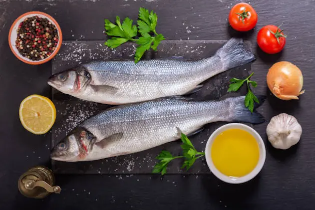 fresh fish with  ingredients for cooking dark background, top view