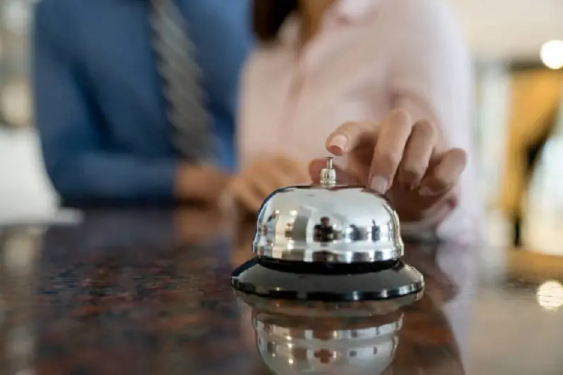 Close-up on a couple ringing the service bell at a hotel from the front desk after doing the check-in