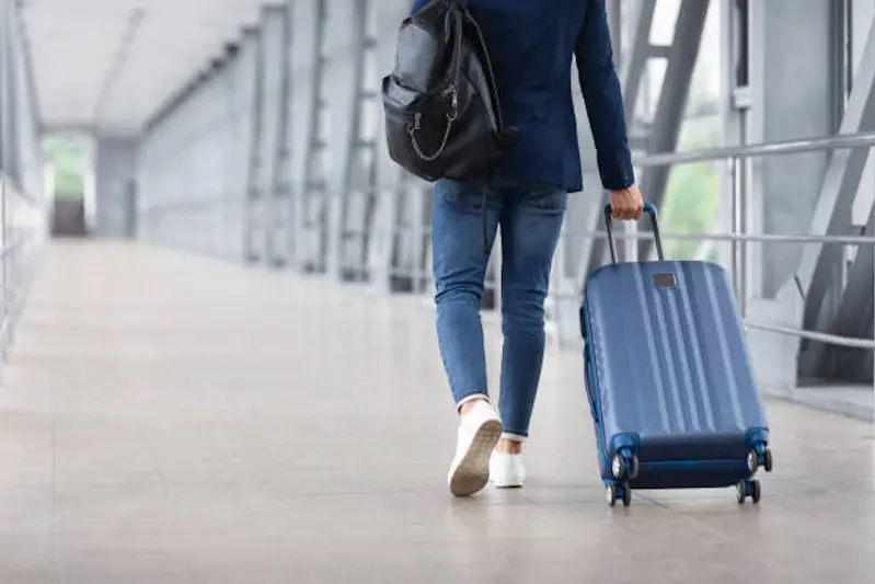 Rear View Of Unrecognizable Man Walking With Suitcase In Airport Terminal, Male Traveller Going To Flight Boarding Gate, Ready For Vacation Journey Or Business Trip, Cropped Image, Copy Space