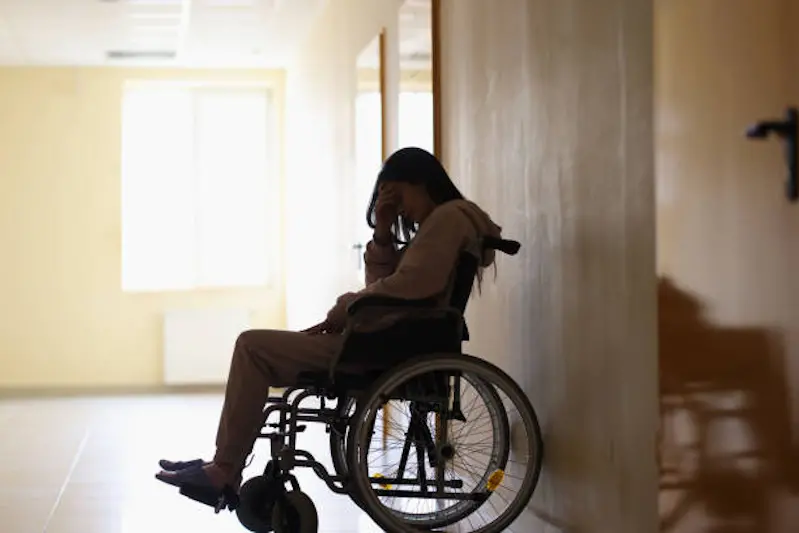 Sad woman disabled sitting in wheelchair and holding her head in clinic. Psychological assistance to people with disabilities concept