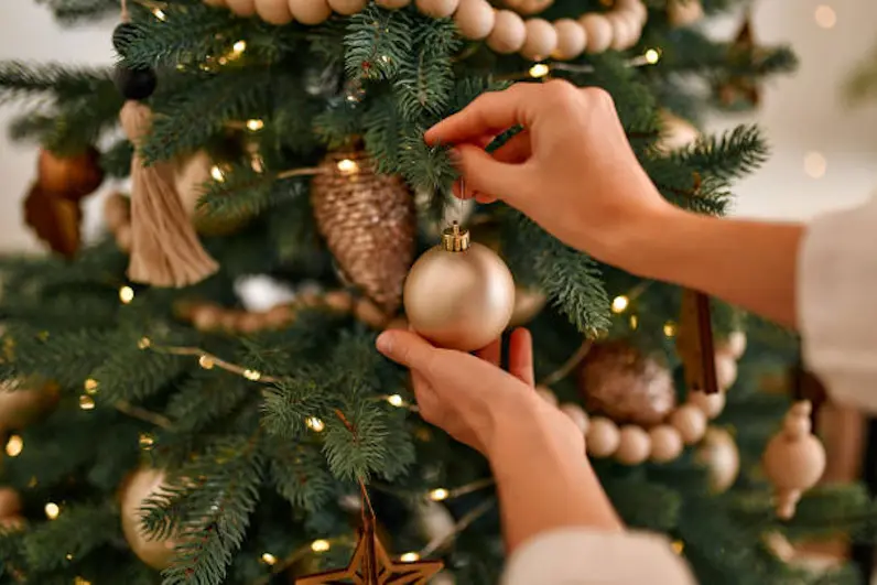 Merry Christmas and Happy New Year! Women\\'s hands decorate the Christmas tree with balls and toys.