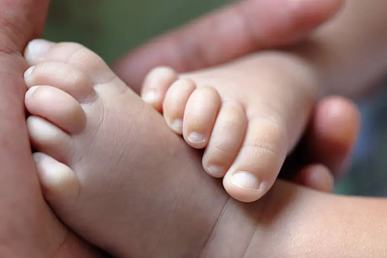 close-up image of feet of an infant held  by hands