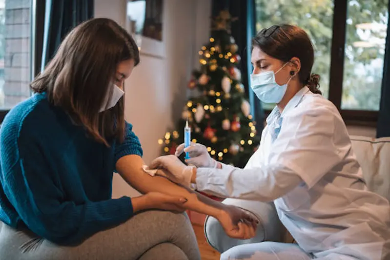 Female doctor injecting antibiotic to patient at her home during Christmas holidays.