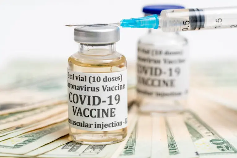 Covid-19 coronavirus vaccine with hypodermic syringe needle sitting on pile of cash to suggest payment for early vaccination