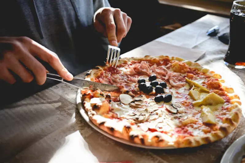 Unrecognizable man eating pizza in a restaurant.