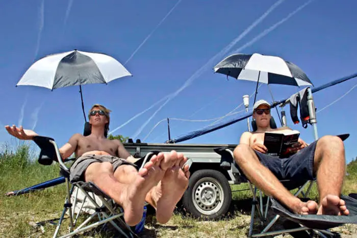 epa000463977 The Swedish crew of a 49 Class sailing boat Jens Hermansson (L) and Jonas Lindberg sit on camping chairs as they wait for gust of wind to come up during the Kieler Woche sailing regatta in Kiel, Germany, Thursday, 23 June 2005. Around 5,000 sailors from 50 countires as well as three million visitors arrived for the world\\'s largest sailing event in Kiel.  EPA/Ulrich Perrey