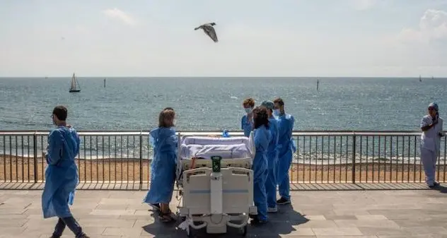 Coronavirus. Medici e infermieri portano i pazienti, in barella, a vedere il mare