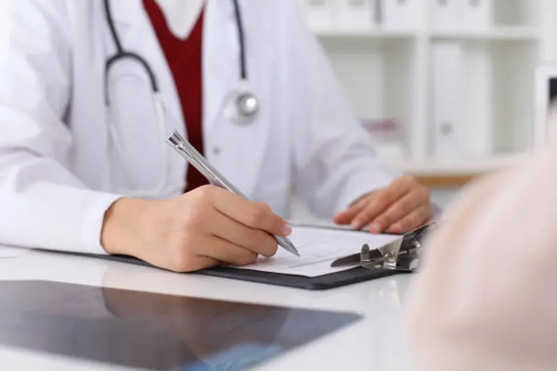 Close up of a female doctor filling up  an application form while consulting patient. Medicine and health care concept