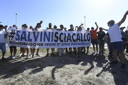 Un gruppo di contestatori mostrano uno striscione \\'Salvini Sciacallo\\' nella zona rossa di Mondragone (Caserta) dove il leader della Lega Matteo Salvini e\\' atteso per un incontro con la cittadinanza, 29 giugno 2020.\\nANSA / CIRO FUSCO