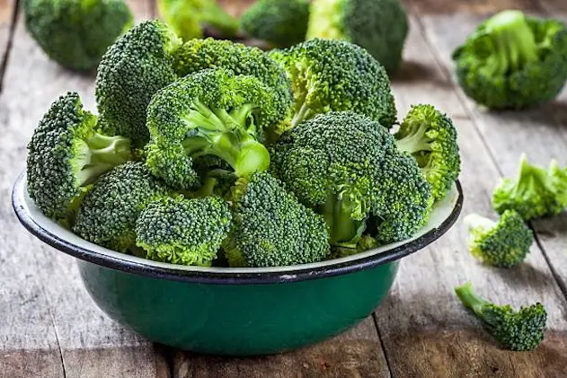 Fresh raw organic broccoli in bowl on wooden rustic background