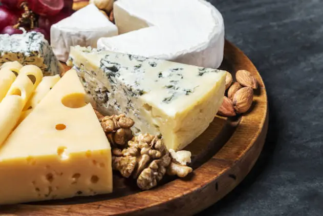 assorted cheeses with mold, Maasdam, Roquefort, brie and others on a wooden table