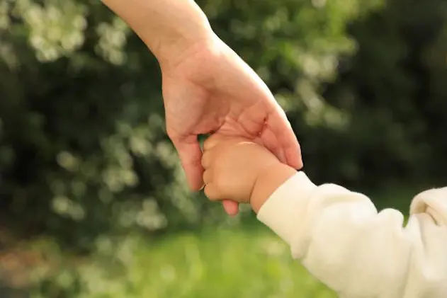 Daughter holding mother\\'s hand in park, closeup. Happy family