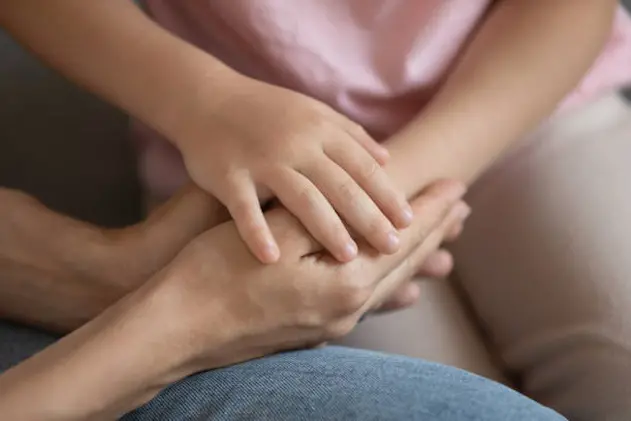 Close up cropped image little daughter putting hand on mommy\\u2019s hands, demonstrating support and care. Young caring woman joined palms with small kid girl. Symbol of love and family understanding.