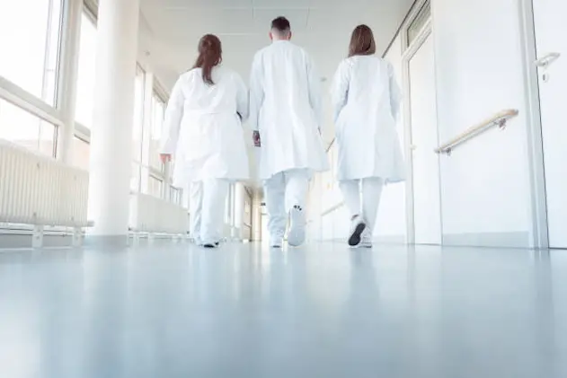 Three doctors walking down a corridor in hospital seen from behind