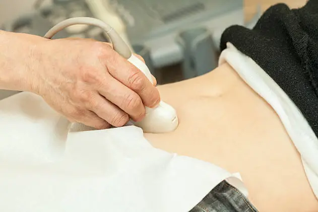 Image of mid adult woman having abdominal ultrasound. Close up of her belly with doctor\\'s hand and ultrasound. selective focus.