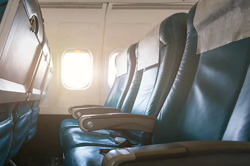 Interior of airplane with empty seats and sunlight at the window. Travel concept.