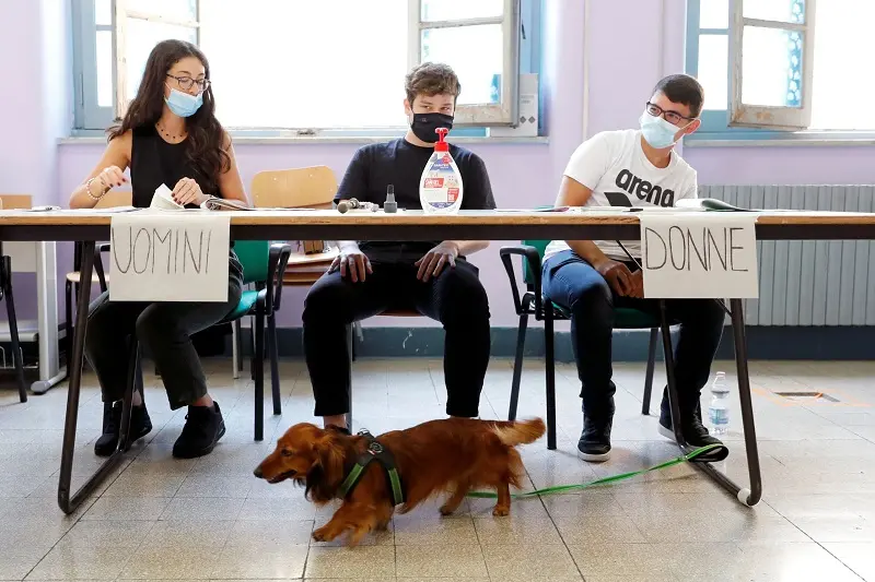 A dog walks in front of election workers during a referendum to sanction a proposed cut in the number of Italian parliamentarians, in Rome, Italy September 20, 2020. REUTERS/Remo Casilli