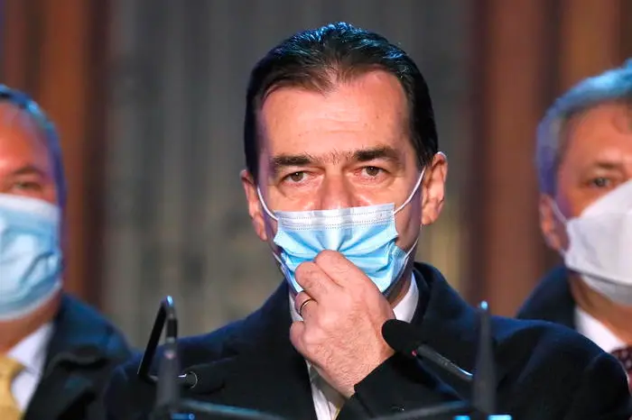 epa08867419 Ludovic Orban, Romania\\'s premier and the leader of PNL (National Liberal Party), flanked by party members, arranges his mask as he delivers a speech after first exit-polls results were announced, at the PNL headquarters, during the parliamentary elections in Bucharest, Romania, 06 December 2020. According to exit polls, PSD (Social Democracy Party) is leading with 30.6%, followed by PNL with 29.1% and the political alliance USR-PLUS with  15.9 %.  EPA/ROBERT GHEMENT