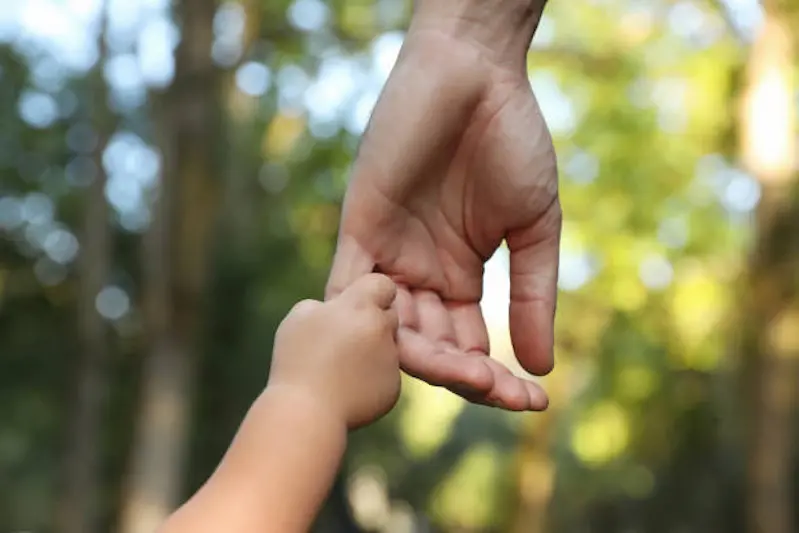 Daughter holding father\\'s hand outdoors, closeup. Happy family