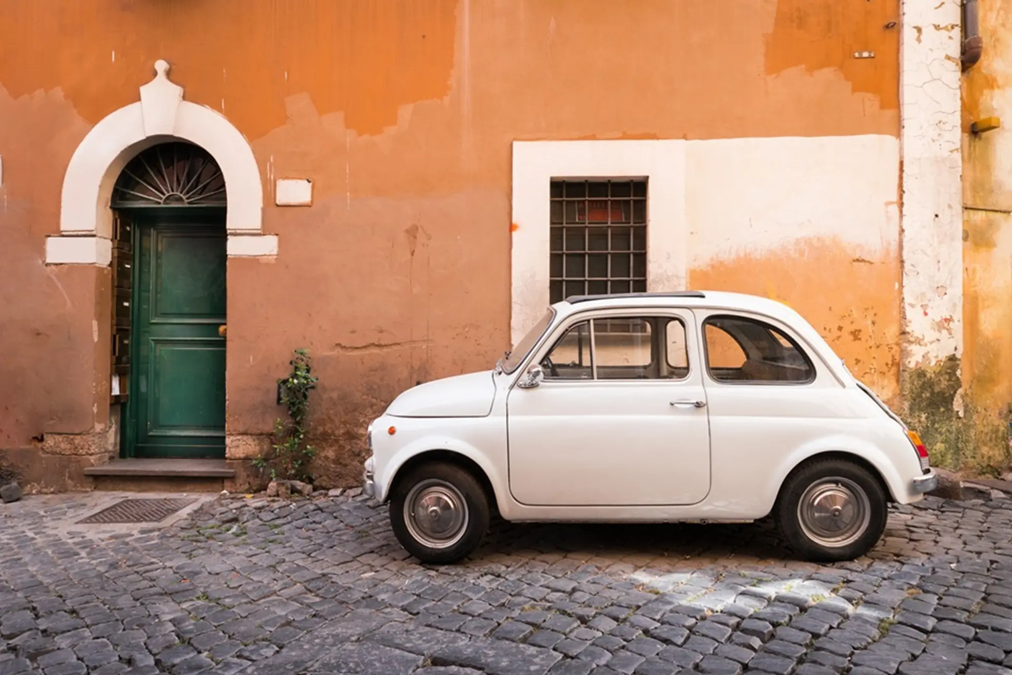Vintage car parked in a cozy street in Trastevere, Rome, Italy, Europe. Trastevere is a romantic district of Rome, along the Tiber in Rome. Turistic attraction of Rome.
