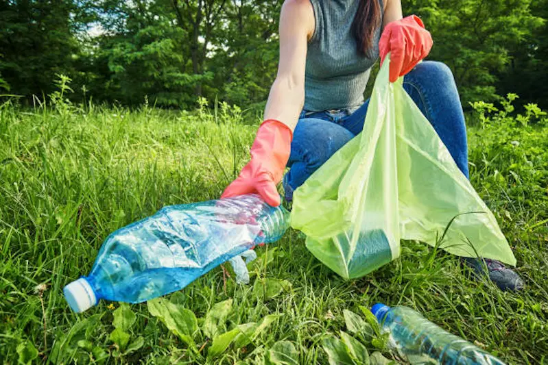 Ecology protection concept. Woman volunteer collecting garbage in park