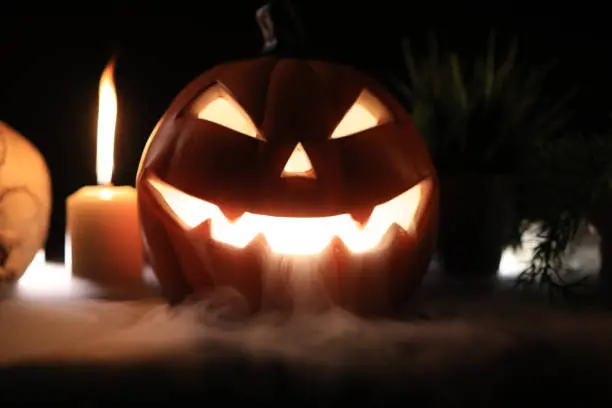 Halloween pumpkin head jack lantern with burning candles  , smoke and Skull monster