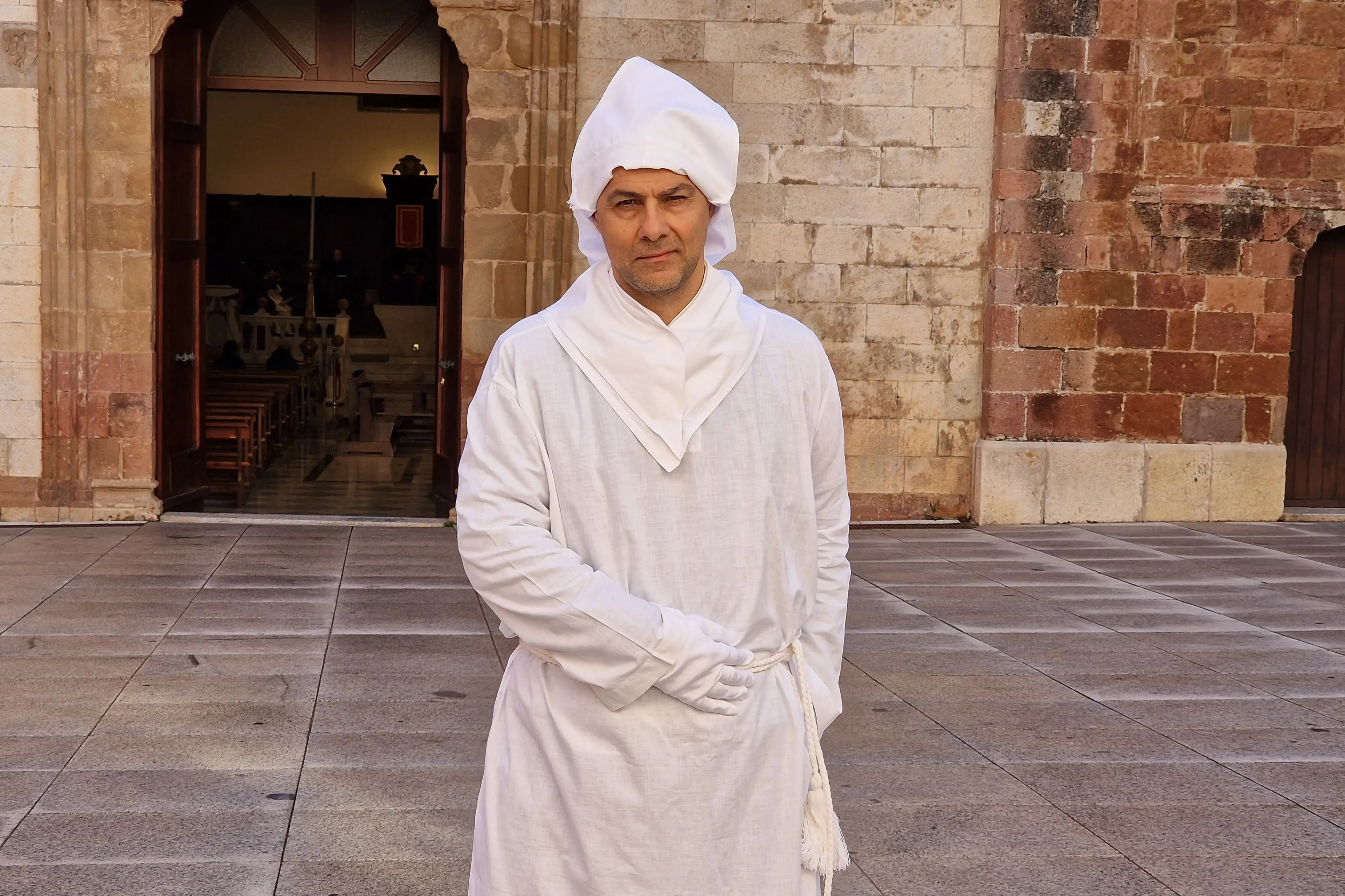 <p>Foto di Luca Mula: Eric Figus con il tradizionale abito da \"baballotto\" davanti alla Cattedrale di Santa Chiara a Iglesias</p>\\n